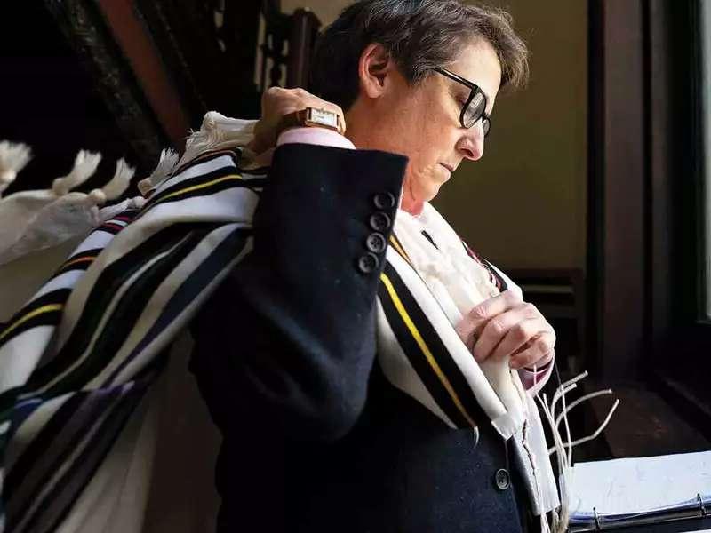 Rabbi Kleinbaum prepares for temple throwing tallit prayer shaw over shoulder